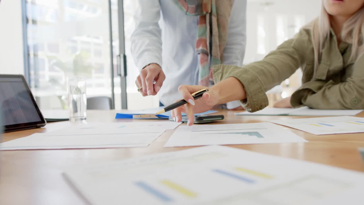 diversas personas de negocios ocupadas discutiendo documentos en la mesa con la tableta en cámara lenta