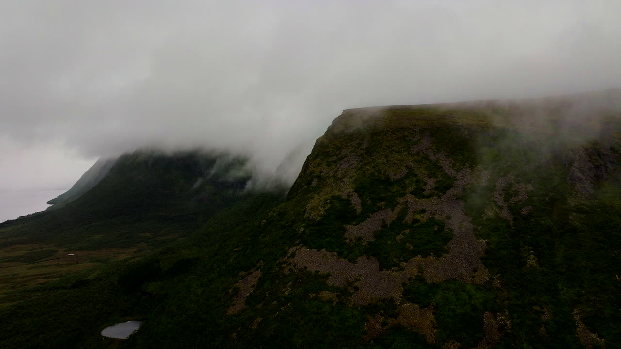 Mountains shrouded in mist and fog in Vesterålen, arctic landscape in northern Norway. Aerial forward
