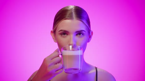 gorgeous woman drinks a tasty macchiato coffee, isolated pink studio background