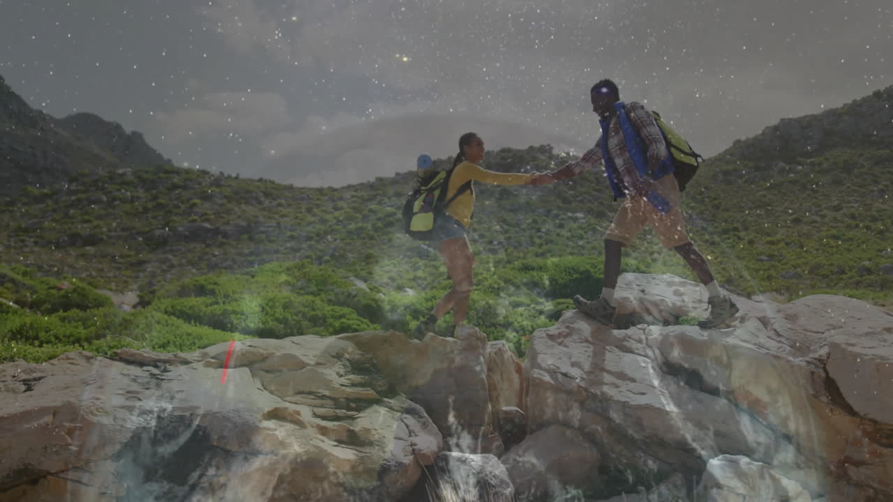 Hiking couple reaching across mountain gap at night showing animated headlamp trails for travel ads