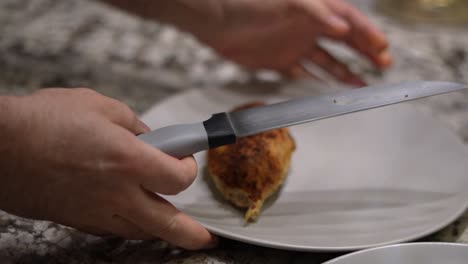 Home-chef-takes-chicken-breast-from-baking-tray-and-puts-onto-empty-plate-dish