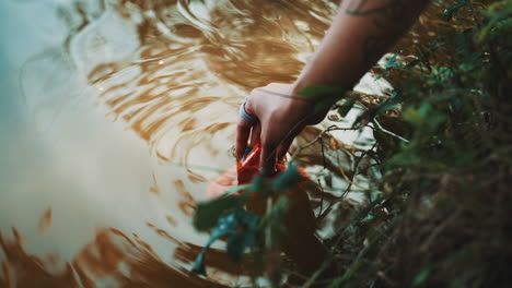 person picking up trash from a lake