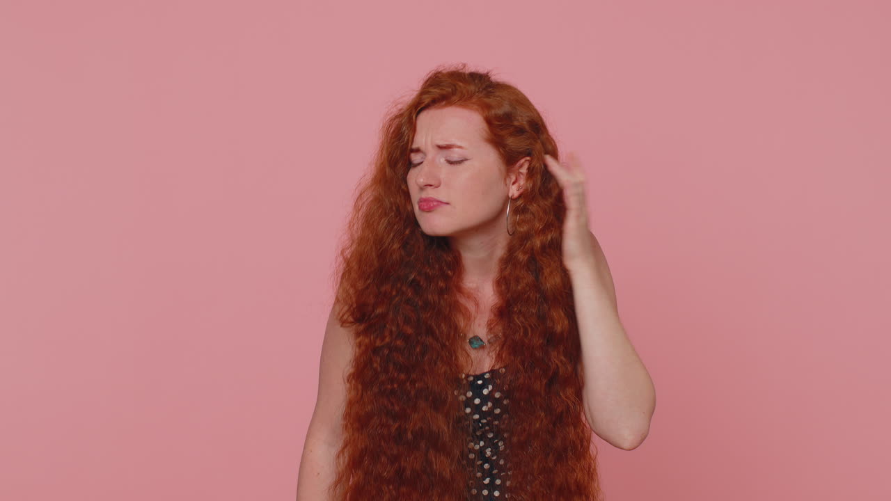 빨간 머리 여자가 당신을 들으려고, 혼란스럽고 눈살을 푸리고, 더 큰 목소리를 위해 귀에 팔을 고 있습니다.