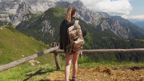 view from behind of a hiker tourist traveler woman with backpack walking n enjoying the view with the dolomites in the background