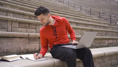 joven estudiante adulto estudiando en el parque usando una computadora portátil.