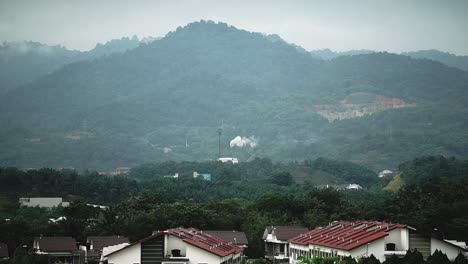 Una-Fábrica-Cerca-De-Una-Cadena-Montañosa_produce-Humo-Blanco_vista-Desde-Un-área-Residencial_toma-Amplia_toma-Larga_50fps