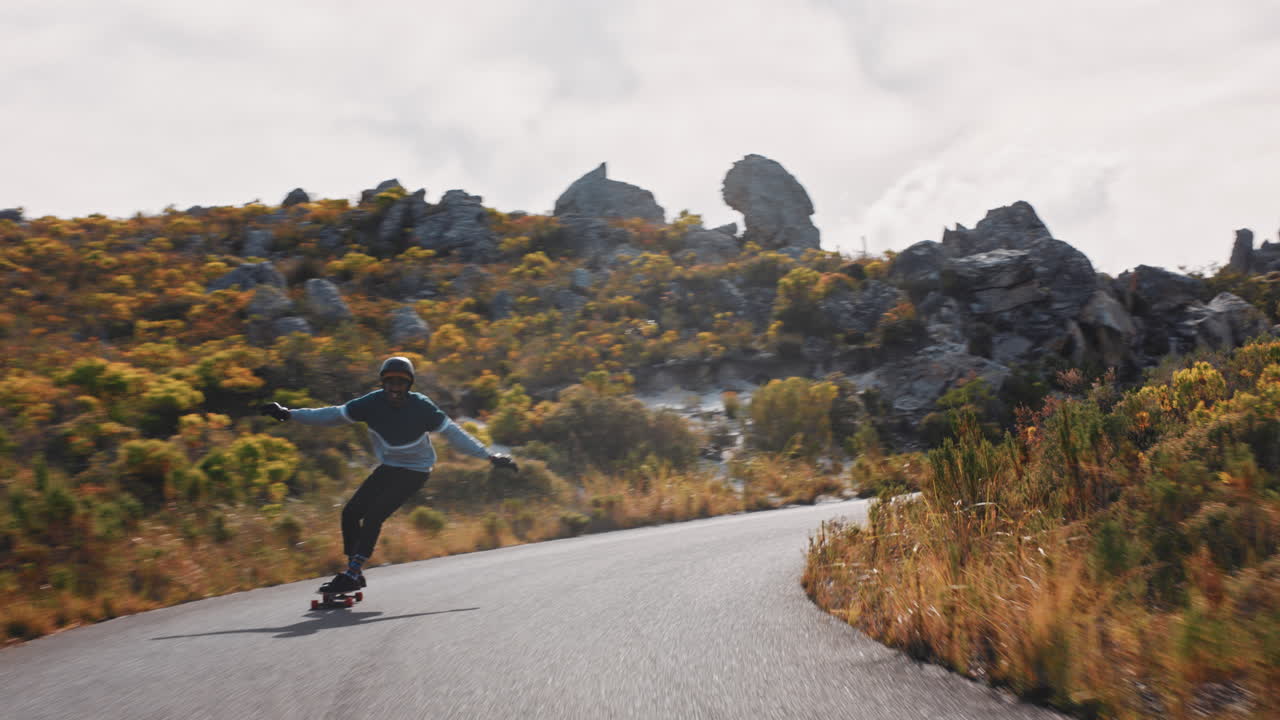 joven feliz montando longboard patinaje rápido disfrutando de la carrera competitiva crucero cuesta abajo en la carretera del campo haciendo trucos usando skateboard usando casco