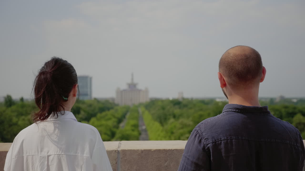 Young couple admiring urban landscape from building roof