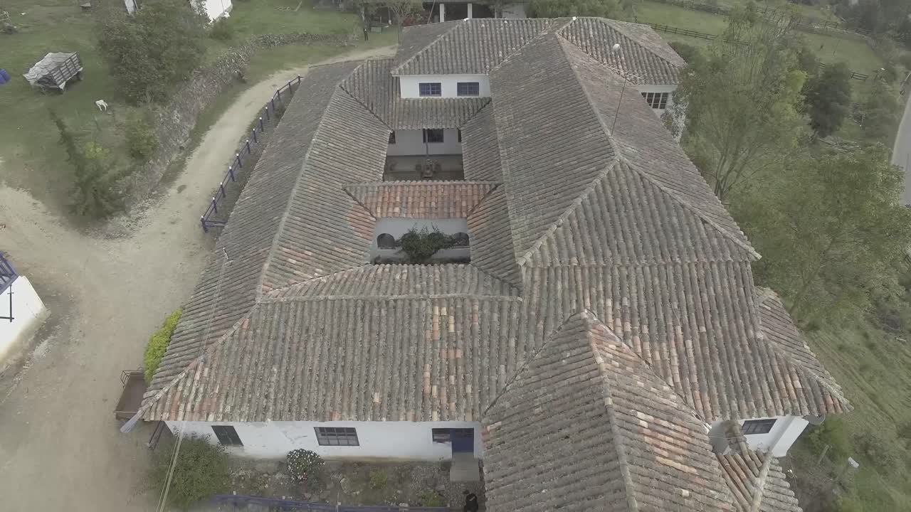 un tiro de ángulo alto vuela sobre una casa de campo con paredes blancas, una persona sale y camina alrededor