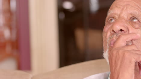 sitting at home, elderly man gazing thoughtfully into distance, copy space