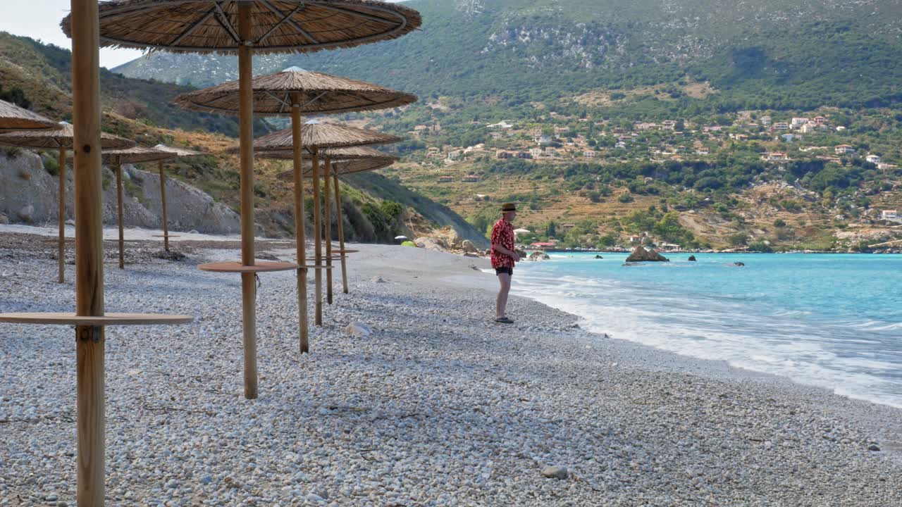 Agia Kiriaki Beach, Zola In Kefalonia, Greece - A Tourist Man Picking Up Pebbles And Throwing Them Into The Sea. - Wide Shot