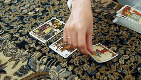 a woman giving a tarot reading with the tower the five of pentacles and the hanged man cards