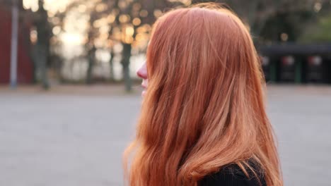 close up profile of young happy red haired woman in 20s in exterior, slow motion