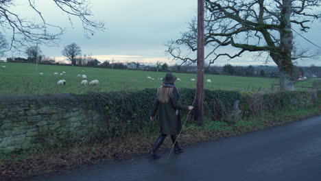 woman walking past field of sheep in countryside