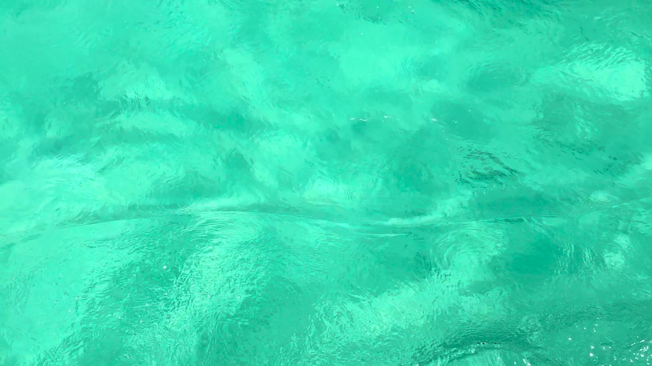 Vibrant turquoise ocean waves gently ripple in Chalong Bay, Phuket, creating a serene and calming visual experience