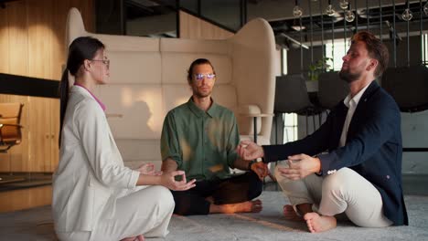 a girl in a white business suit, a guy in a green shirt and a man in a blue jacket are meditating during a break from work. zen practice for harmony with yourself while working