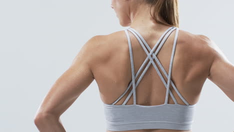 close-up of a young caucasian woman athlete's back, showcasing sportswear on a white background