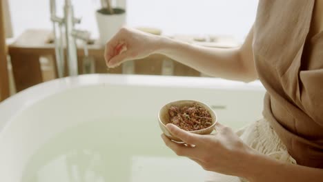 Hands-close-up-of-a-woman-preparing-and-adding-natural-scents-to-the-bathtub,-spa-treatment-concept-with-copy-space