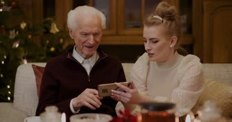 woman teaching grandfather to use smartphone in christmas 1