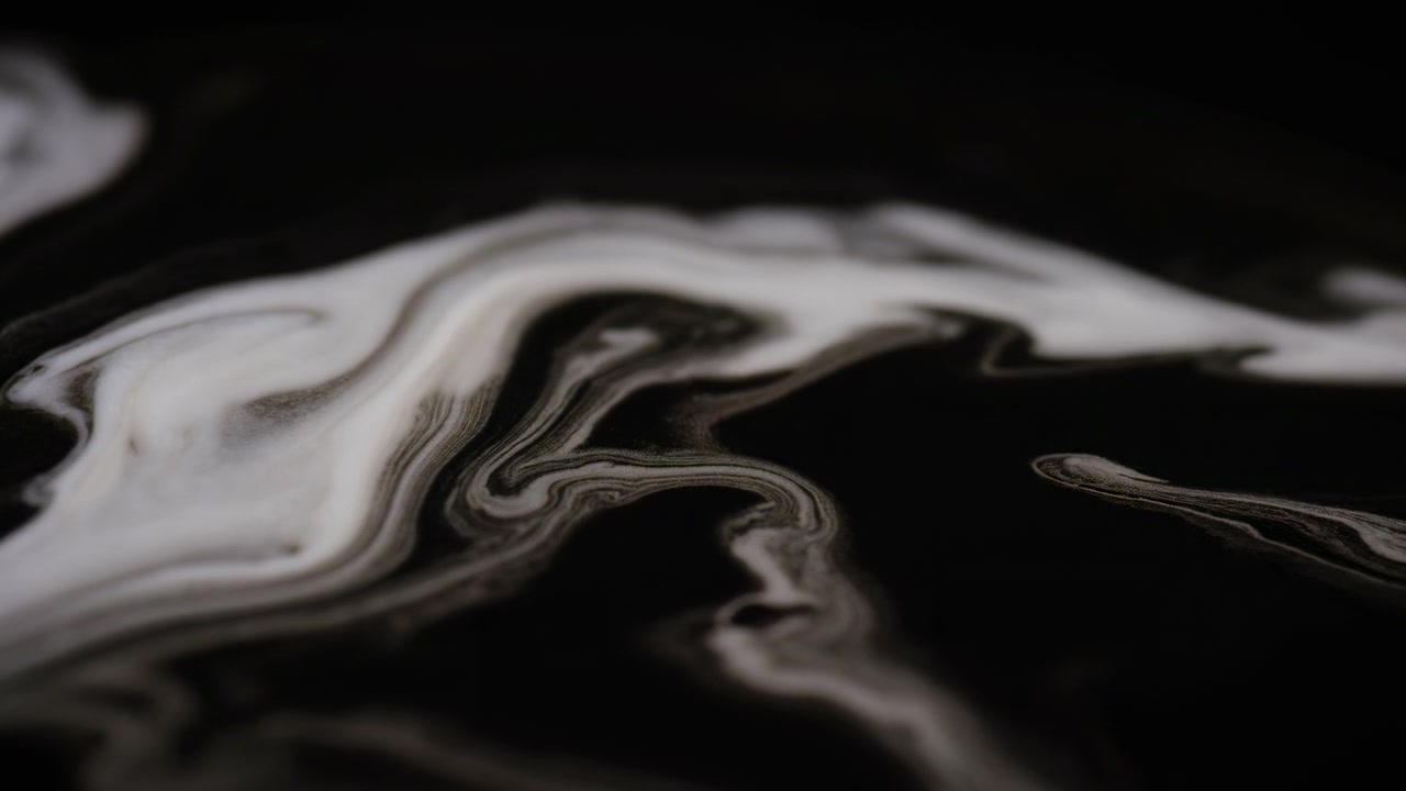 Vista ravvicinata in movimento da un'angolazione bassa di vortici simili a nastri bianco crema e grigi su una superficie nera intensa, con sottili separazioni, bordi smerlati, fasce stratificate, morbide luci e canali scuri.