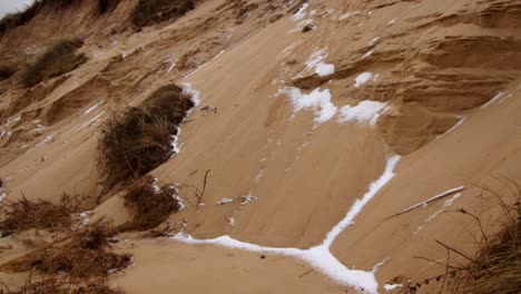 erosión costera de sandunes con nieve en la playa de hemsby, plano medio