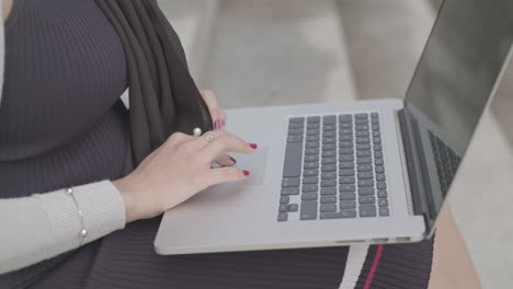 close up shot of a woman typing on a laptop outside in slowmotion - ungraded