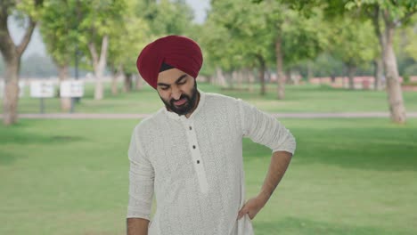 sick sikh indian man suffering from back pain in park