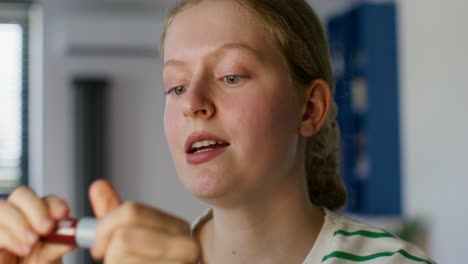 teenager applying lipstick