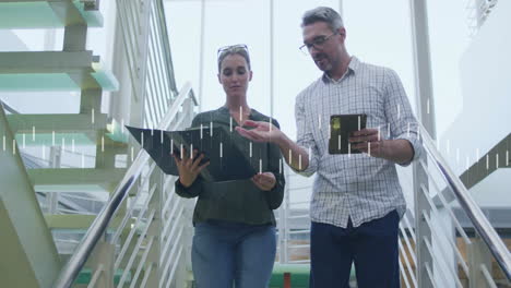 Animation-of-processing-data-over-caucasian-male-and-female-colleague-talking-on-stairs-at-office