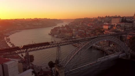 aerial sunset drone footage of porto city of portugal golden hours bridge over the douro river electric tram train cross the town and scenic bird flying