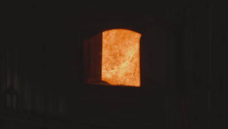 Flame-burns-in-industrial-furnace-chamber-with-open-door