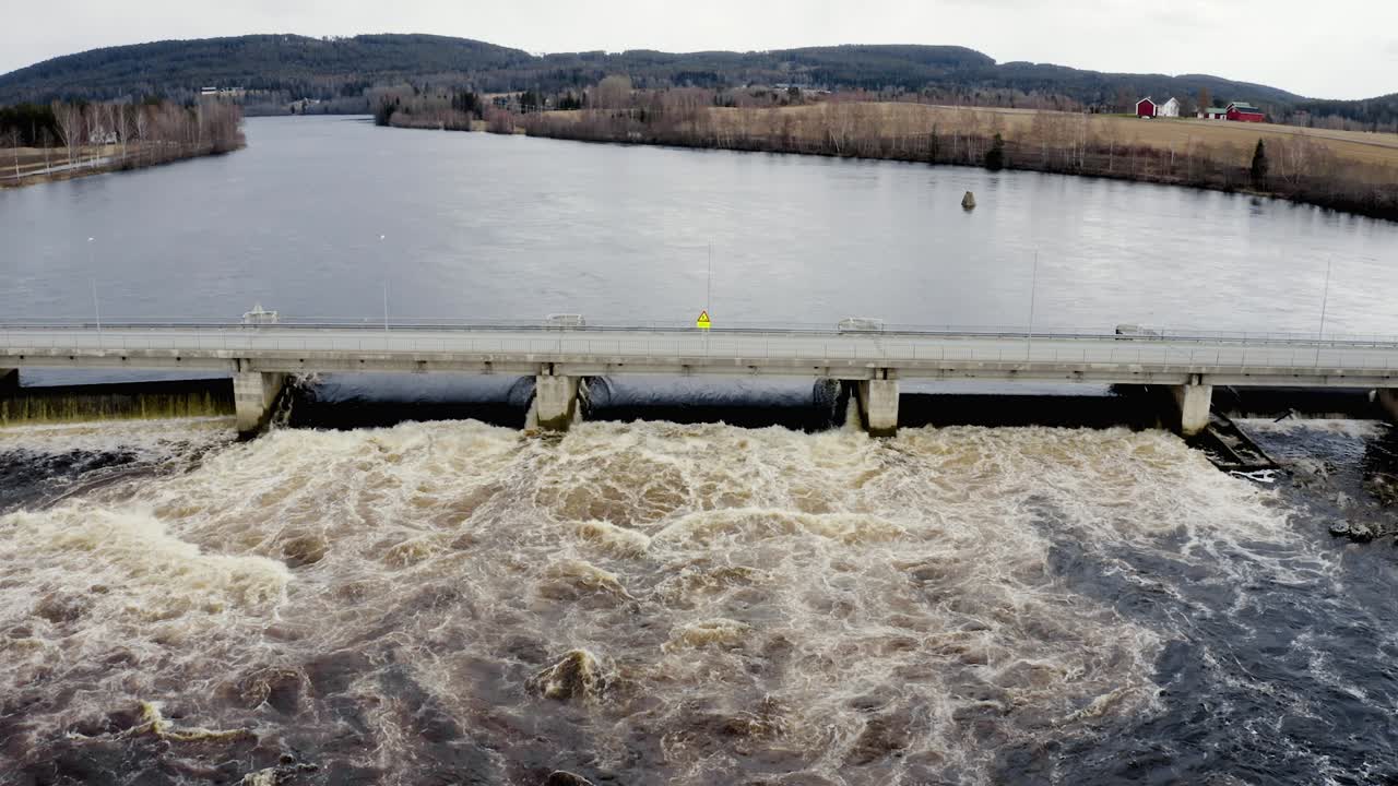 Static aerial shot of a river flowing underneath a bridge.
