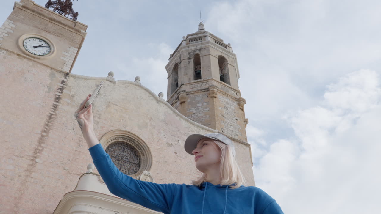 студентка снимает, делает селфи на телефоне в отпуске с великолепным большим церковным собором на заднем плане, старой европейской архитектурой с небом