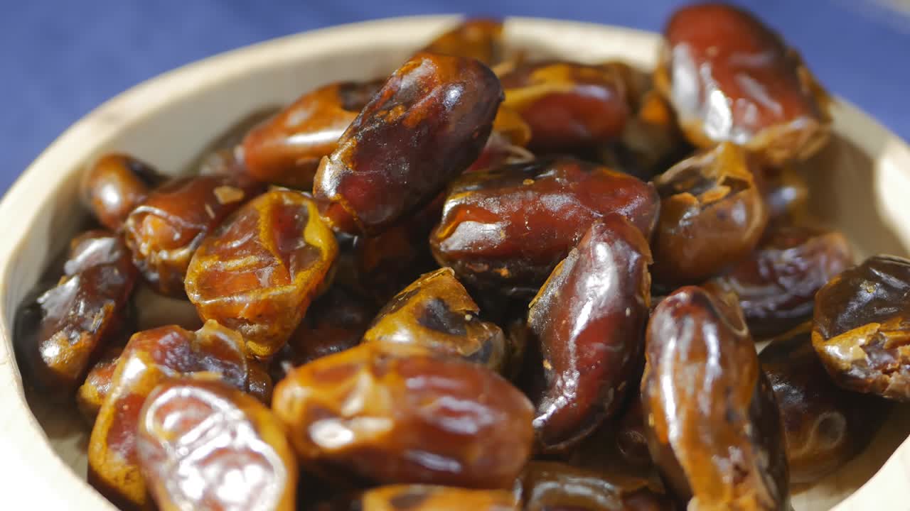 Close-up, DOF, circular rotation: Sweet dried dates in a wooden bowl