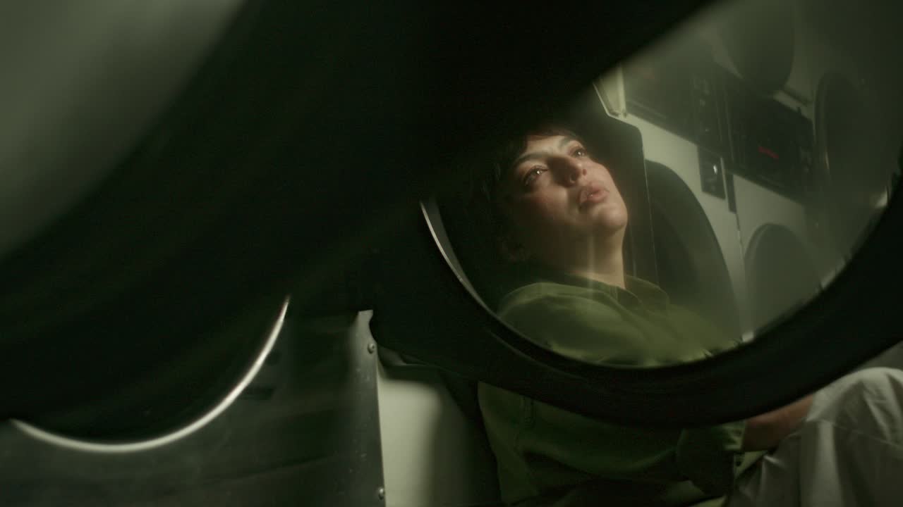 una mujer triste, sufriendo la inquietante rutina del servicio de lavandería, sentada en el suelo, muy triste sintiéndose sola