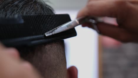 extreme close-up as a barber finishes up blending a fade on a male customer's haircut