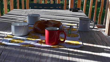 cups of hot tea with evaporating water and a bun, wooden table, terrace of a hut