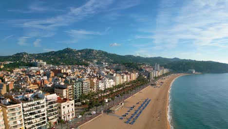 Impresionante-Vista-De-La-Plaza-Principal-De-Lloret-De-Mar-En-La-Costa-Brava-De-Gerona,-Ayuntamiento-Y-Paseo-Marítimo-En-Primera-Línea-De-Playa-Con-Tumbonas-Con-Poca-Gente-Dispuestas.