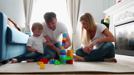 happy family dad mom and baby 2 years playing lego in their bright living room. slow-motion shooting happy family