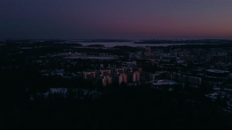 forward aerial of forest and snowy neighborhood in finland at dusk