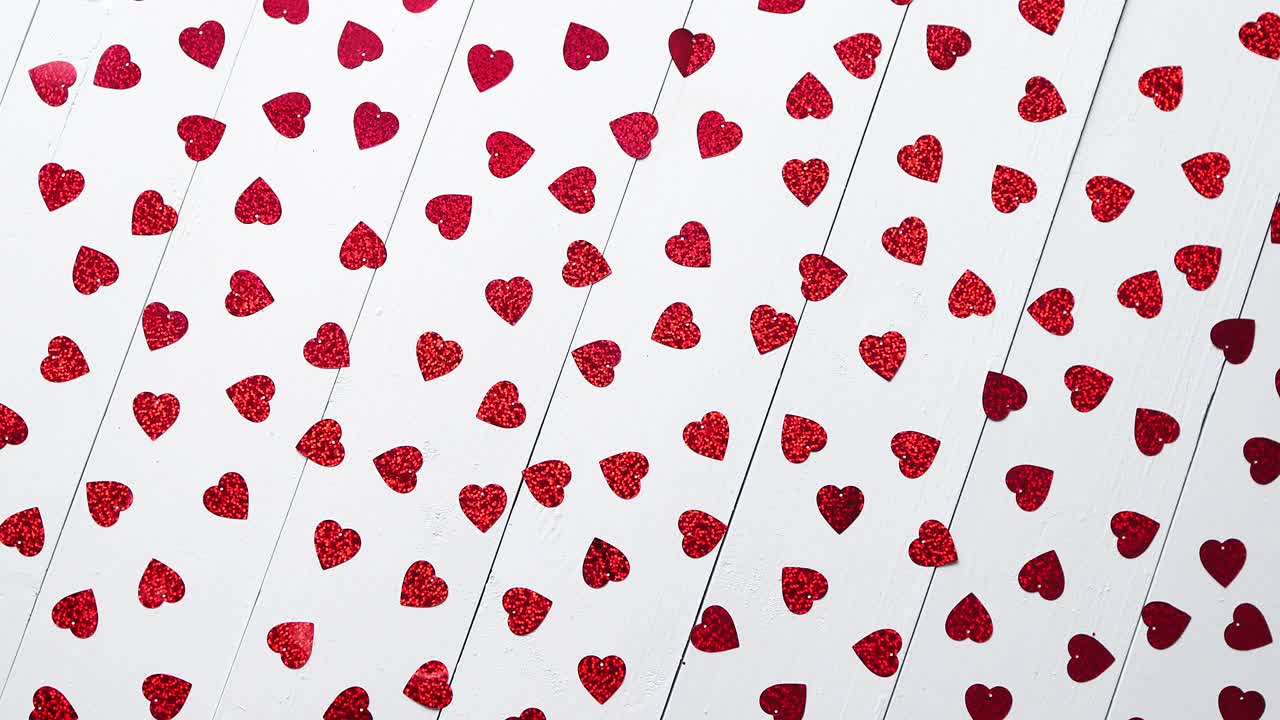 Composizione per San Valentino: paillettes a forma di cuore poste su un tavolo di legno bianco