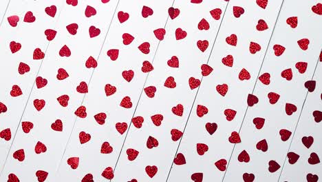 Vlentine's-Day-composition--Heart-shaped-sequins-placed-on-white-wooden-table