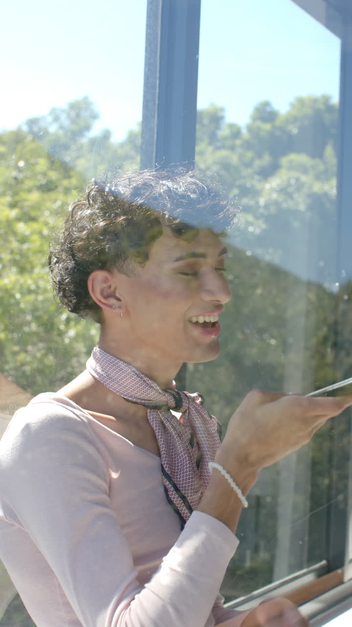 Vertical video: Smiling person using smartphone voice command near window at home