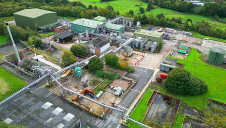 Aerial-video-nears-a-UK-chemical-plant,-displaying-pipelines,-metal-frameworks,-cooling-towers,-and-chemical-storage