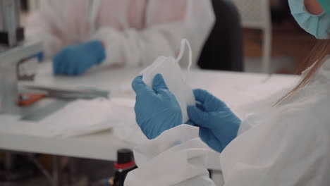 a man in a protective suit and gloves folds face masks