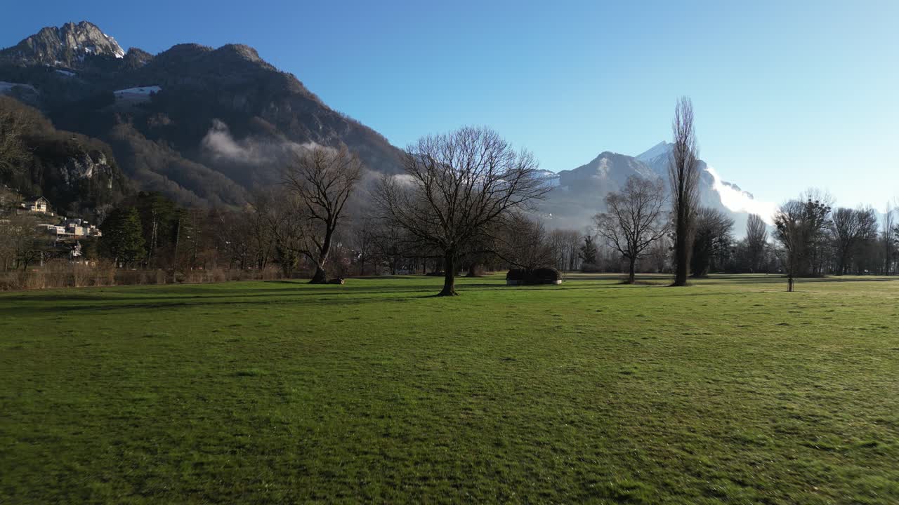 Ripresa aerea dal basso di una montagna con un campo verde in primo piano nel Walensee, Svizzera.