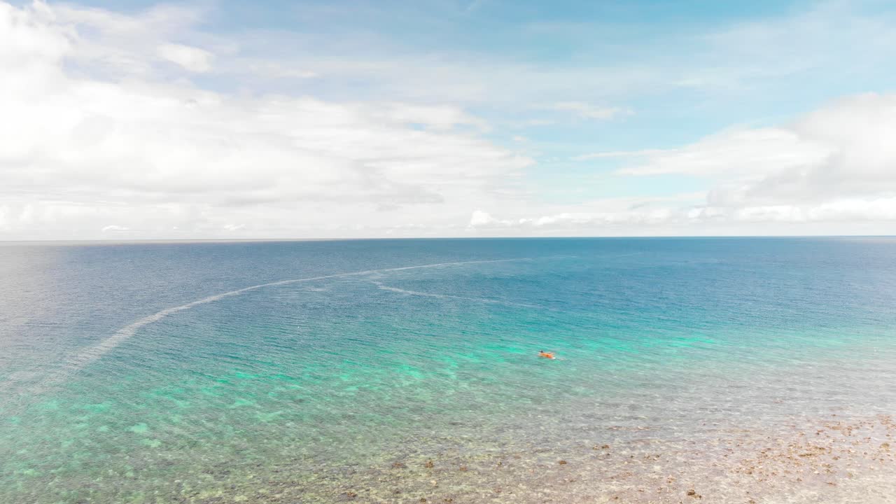 푹신한 흰 구름과 푸른 하늘 아래 열대의 열린 밝은 푸른 바다에서 낚시 펌프 보트 위로 날아가는 드론