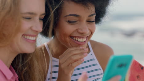 Schöne-Frau-Mit-Afro,-Die-Wassermelone-Am-Strand-Isst-Und-Für-Einen-Freund-Posiert,-Der-Mit-Dem-Smartphone-Ein-Foto-Macht.-Freundinnen-Teilen-Den-Sommertag-In-Den-Sozialen-Medien-Und-Haben-Spaß-Am-Meer-In-4K