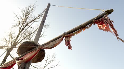 wooden pole with a red sail hanging from it, set against a clear blue sky