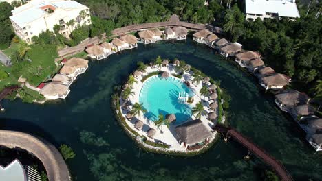 Vista-Aérea-De-La-Hermosa-Isla-De-La-Piscina-En-La-Laguna-Rodeada-De-Bungalows-Y-Selva-Tropical,-Playa-Del-Carmen,-México